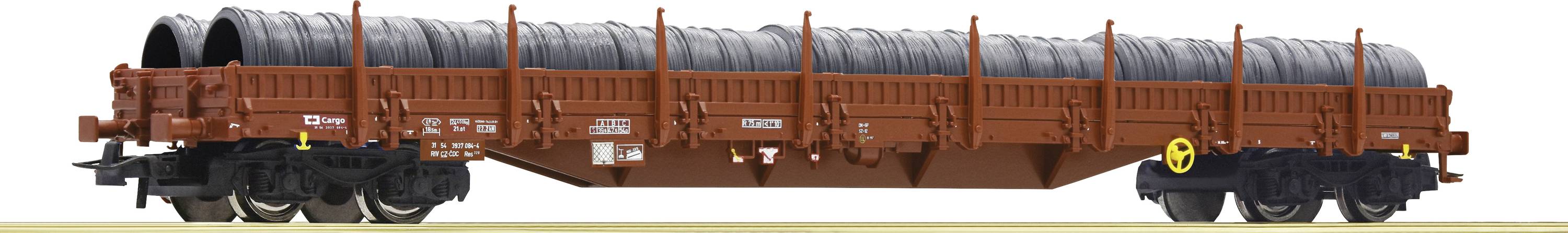 A goods wagon is transporting several large steel coils. The wagon is rusty brown and is positioned on a section of railway track.