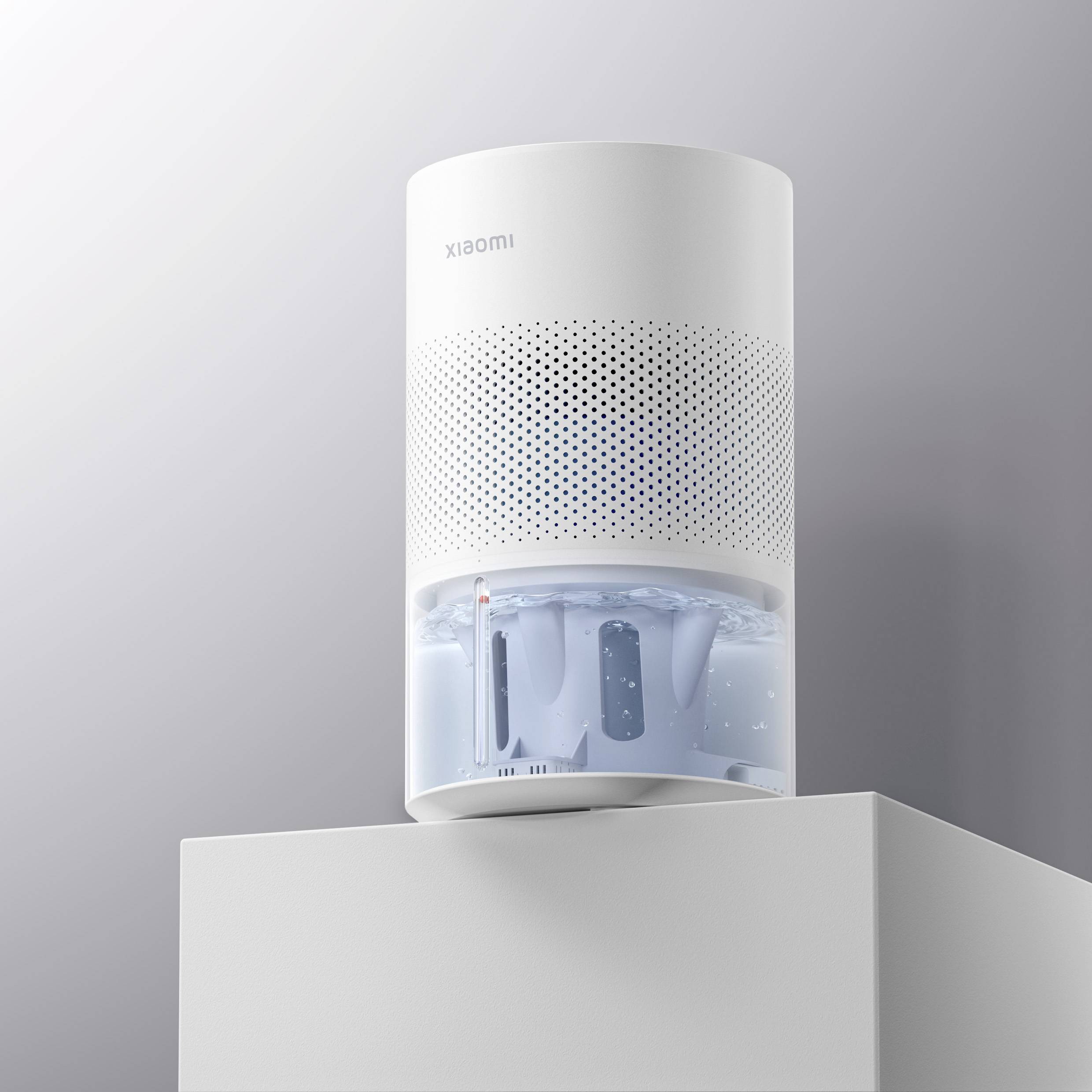 A white, cylindrical air purifier on a table. The water reservoir is visible in the lower third.