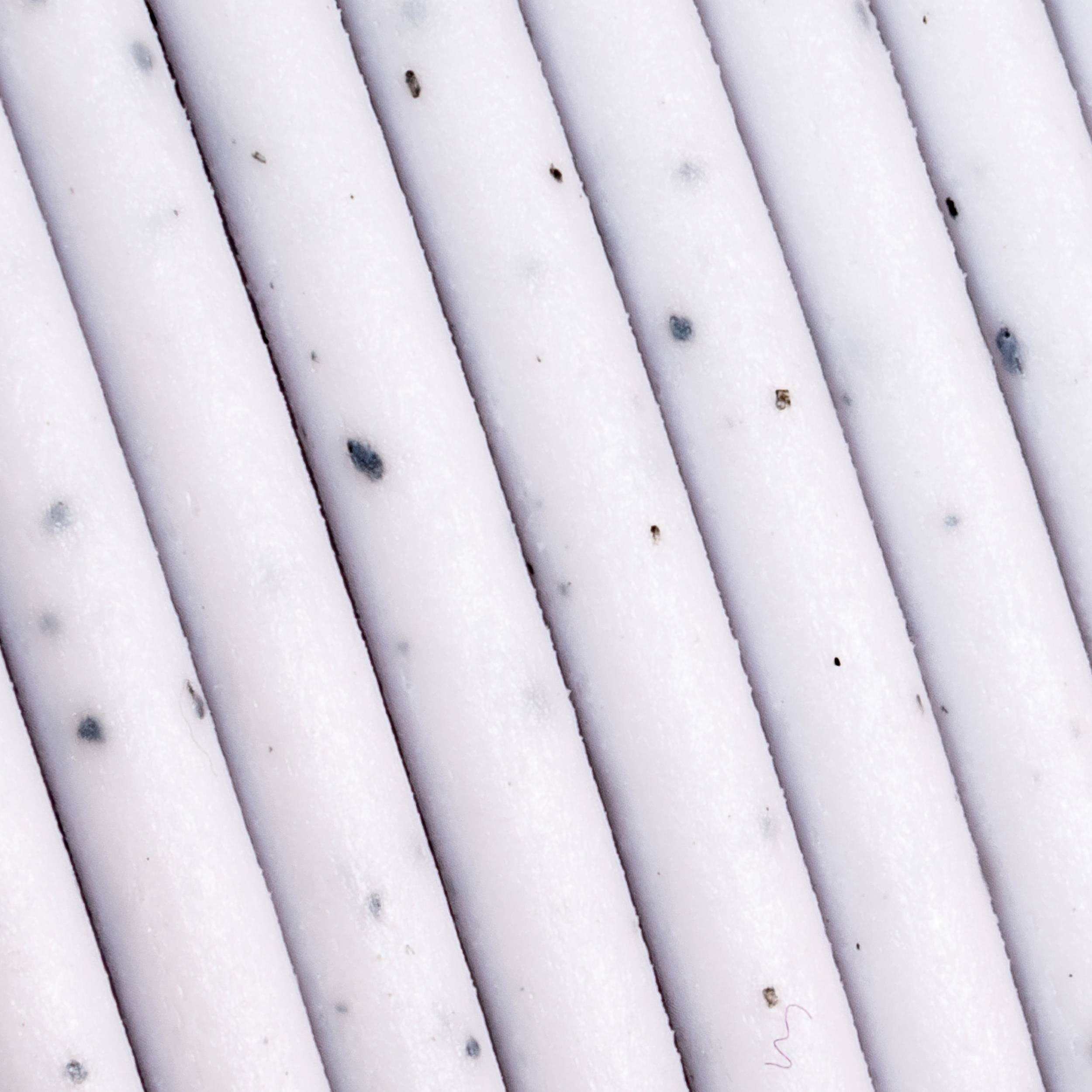 Close-up of several white, striped straws with scattered black dots on the surface.