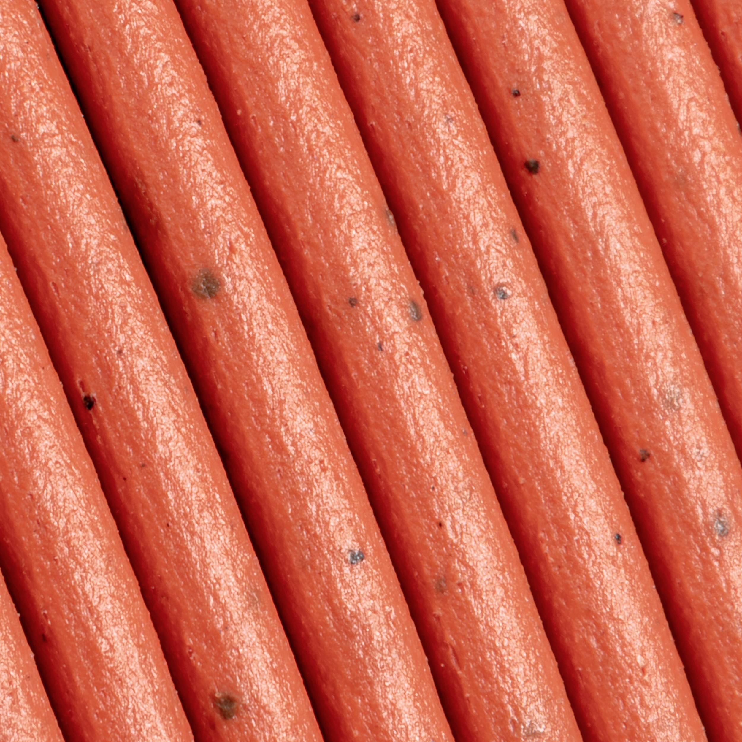 Close-up of smooth, orange-colored cables running parallel to each other. The surface shows small dark spots.