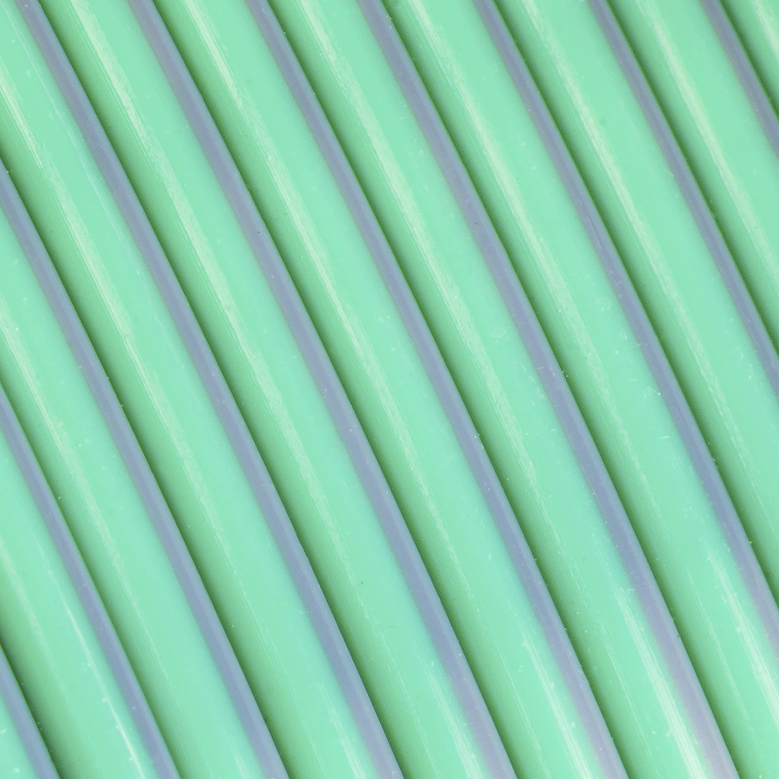 Green plastic pipes arranged in parallel lines close together.