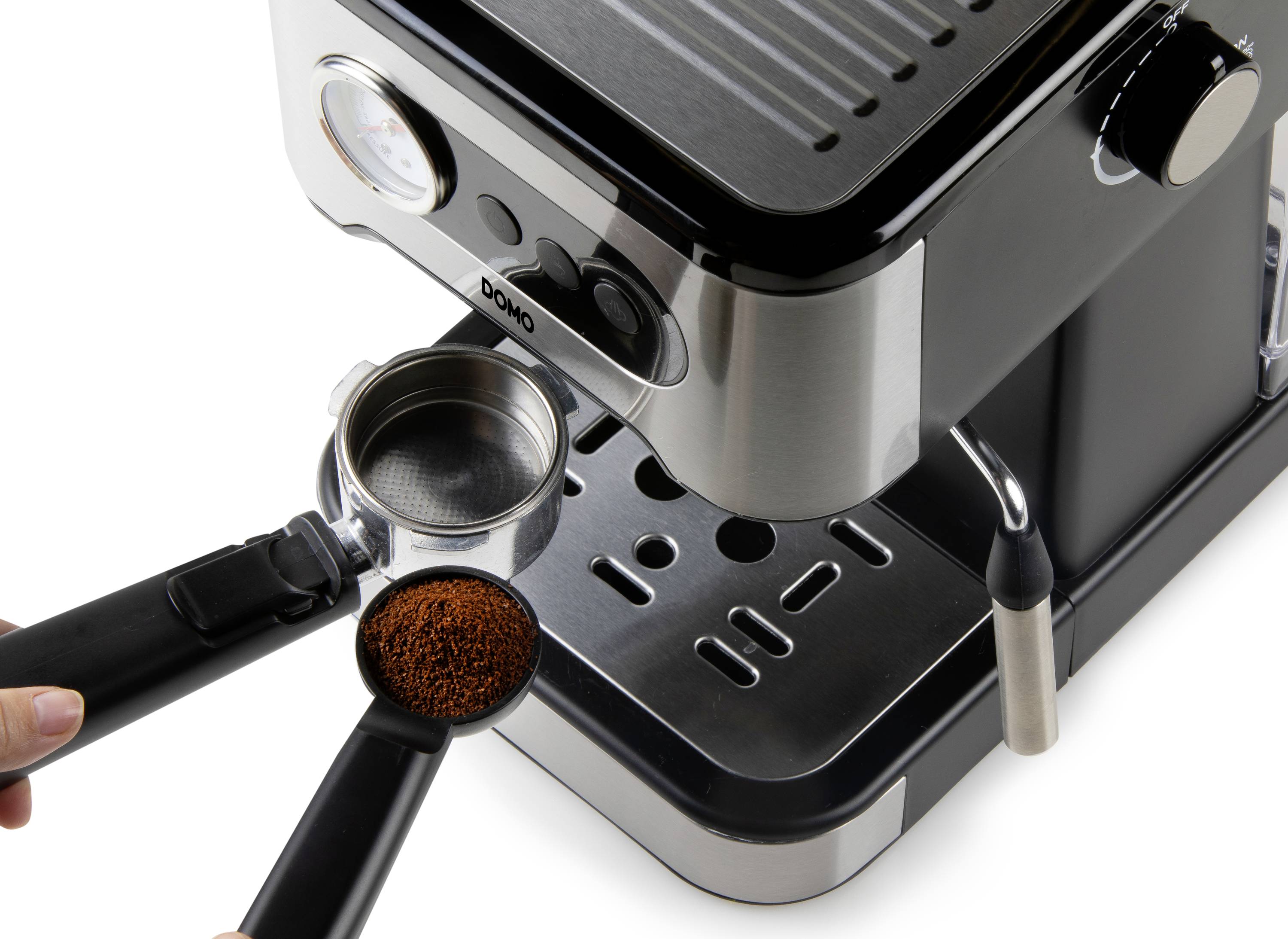 A person is filling coffee grounds into the portafilter of an espresso machine. The machine has a metallic body with a black finish.