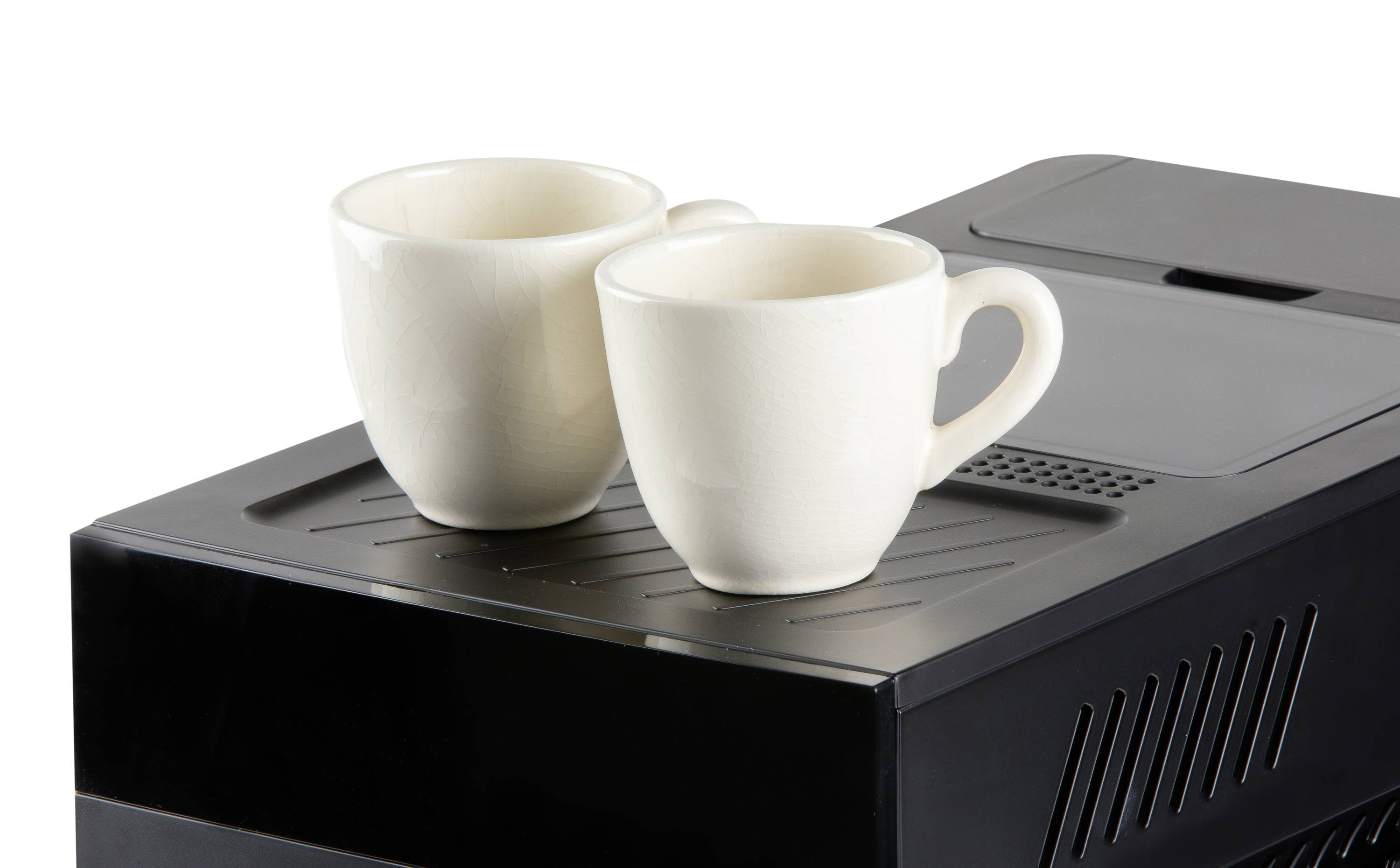Two white cups are standing on a black fully automatic coffee machine. The cups are empty and ready to be filled with coffee.