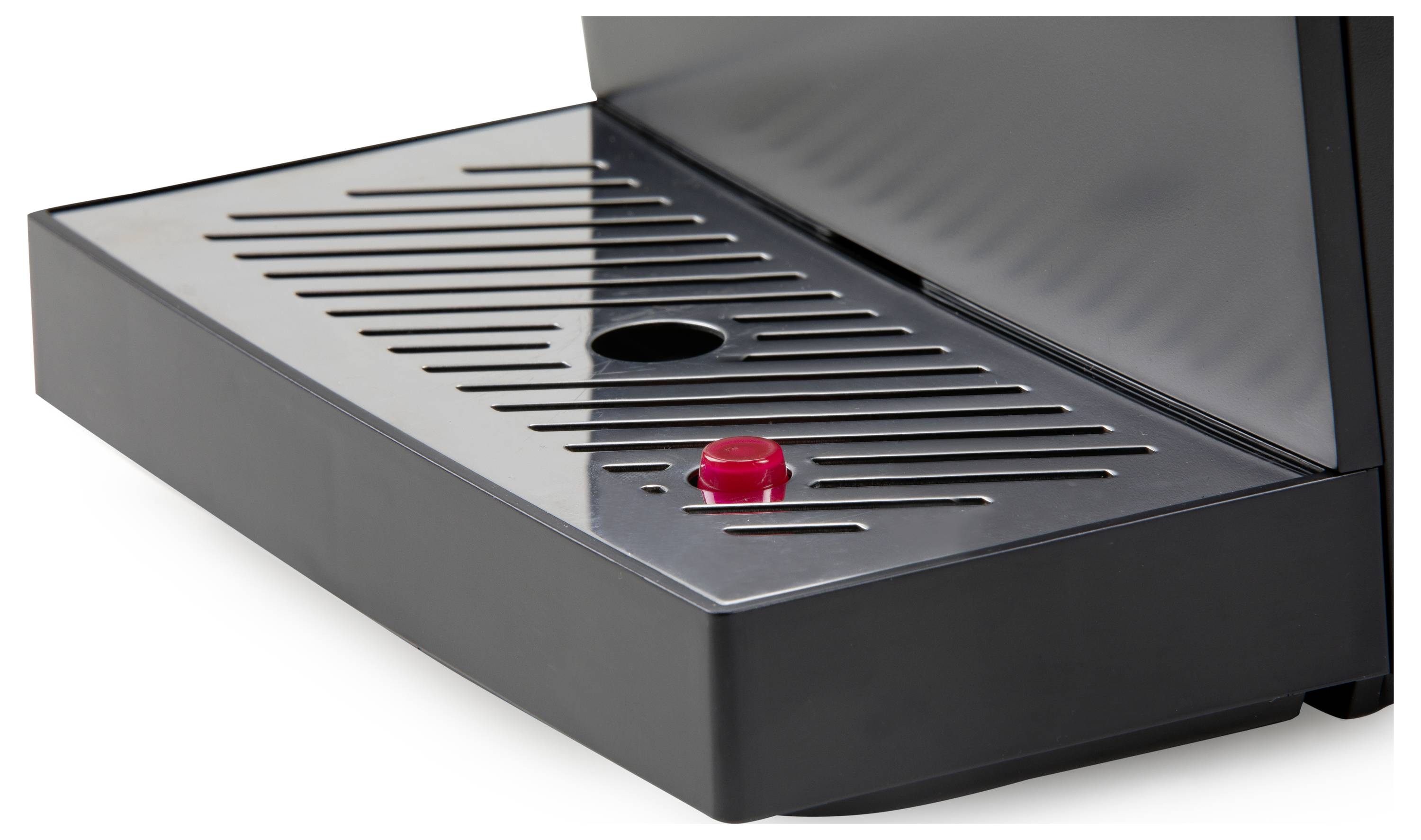 A close-up of a black drip tray with a red button in the centre, part of a coffee machine.