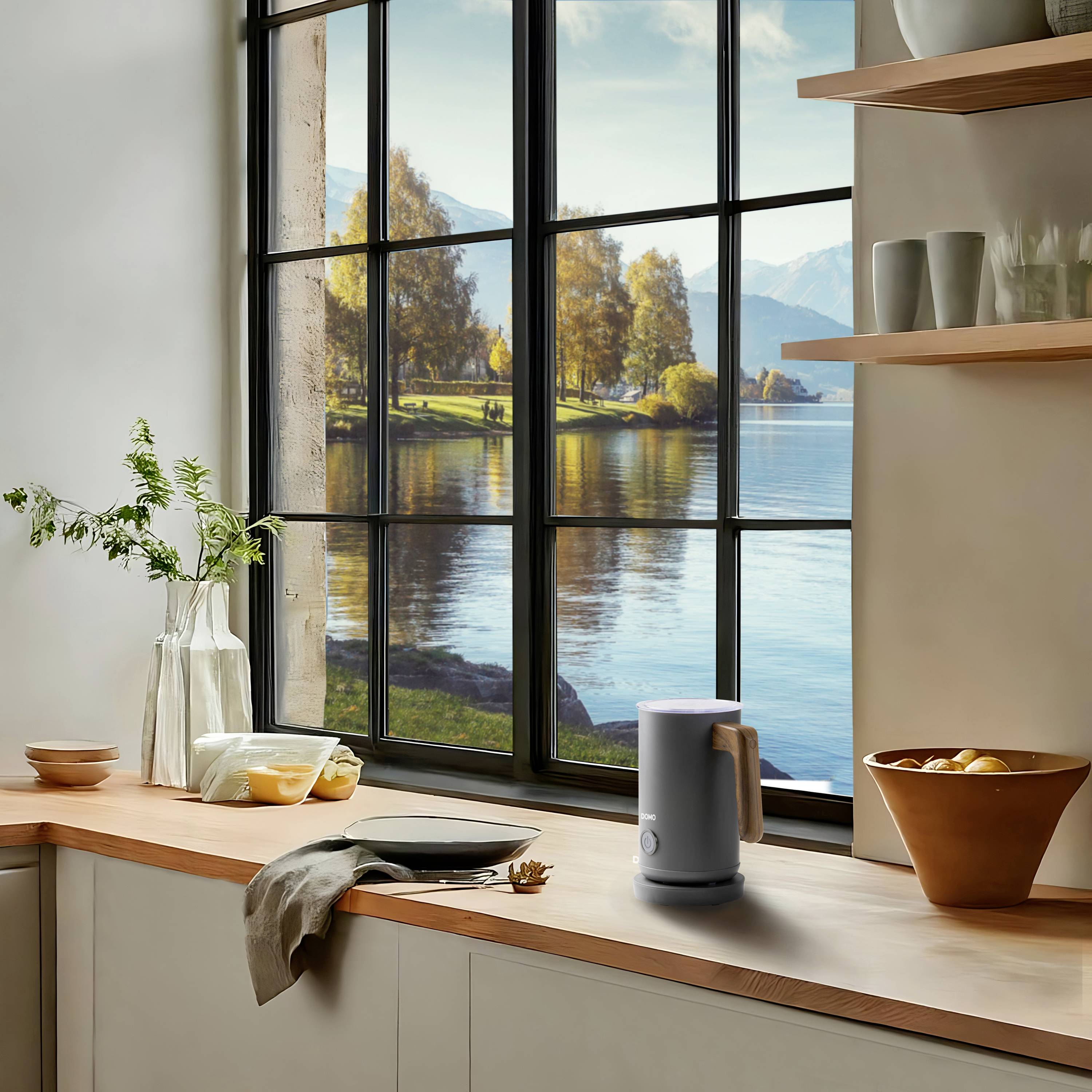 A modern kitchen with a view through a large window overlooking a picturesque landscape of a lake and mountains. Vessels are placed on the worktop.