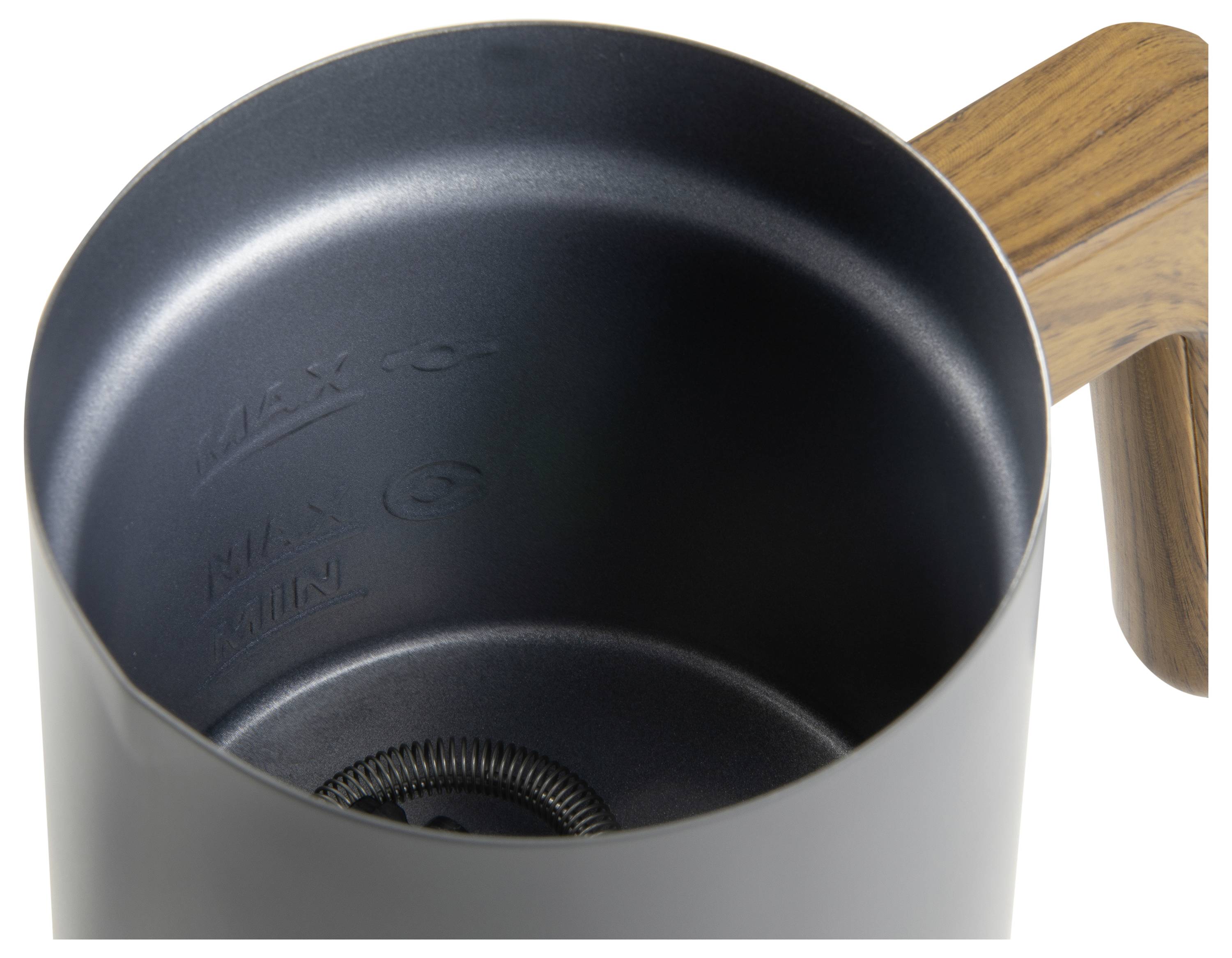 Top view of a black metal milk jug with a wooden handle. Inside, markings for the maximum and minimum fill levels are visible.
