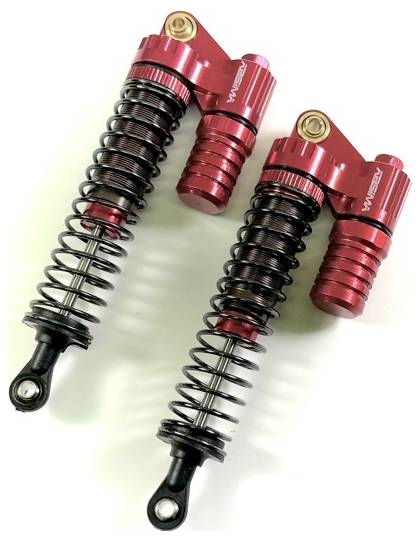 Two red shock absorbers with suspension, lying side by side. They are made of metal and serve to dampen vehicle vibrations.