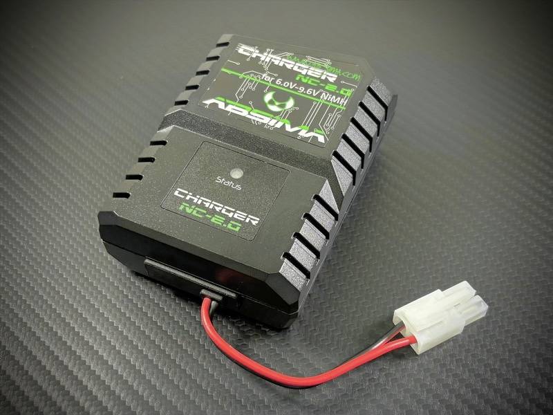 A black charger for 6.0 to 9.6 V NiMH batteries on a dark surface. It has red and white connecting cables.