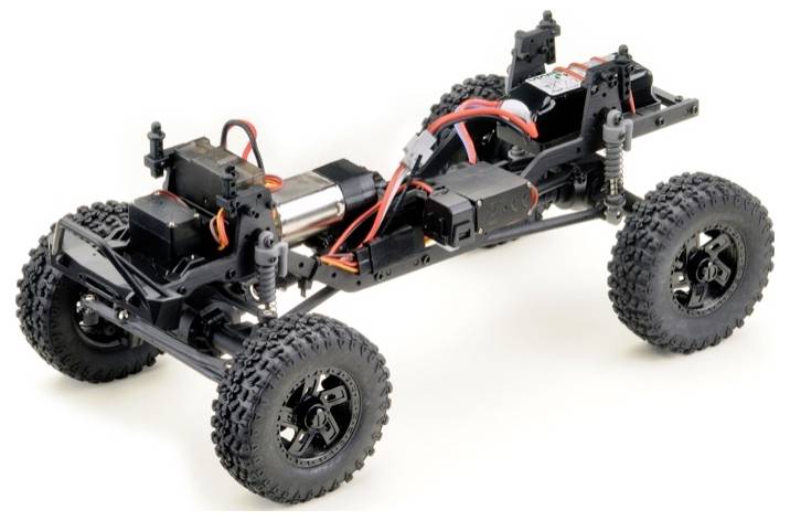 A remote-controlled four-wheeled car chassis with visible electronics, cables, and suspension, ready for assembly.
