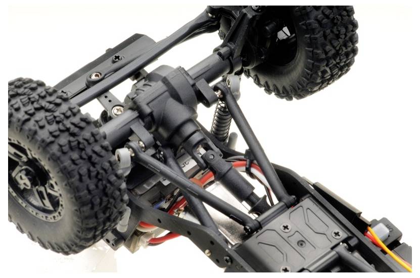 Close-up of an off-road vehicle chassis with suspension and chunky tyres, revealing details of the suspension and wiring.