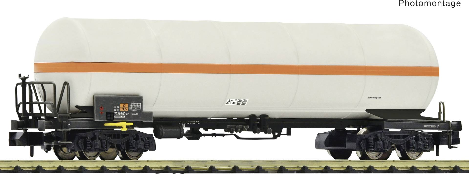 A goods wagon model with a large, white tank and an orange line, standing on railway tracks.
