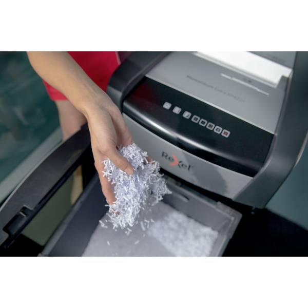A person is shredding documents with a shredder. White paper falls into a collection bin, the action showing document destruction.