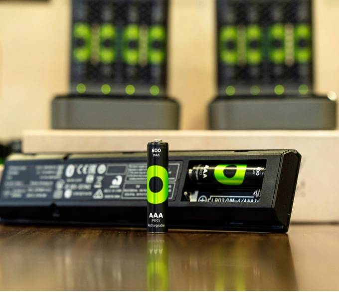 An environmentally friendly AA battery with 800 mAh is inserted into a charger. Several similar chargers can be seen in the background.