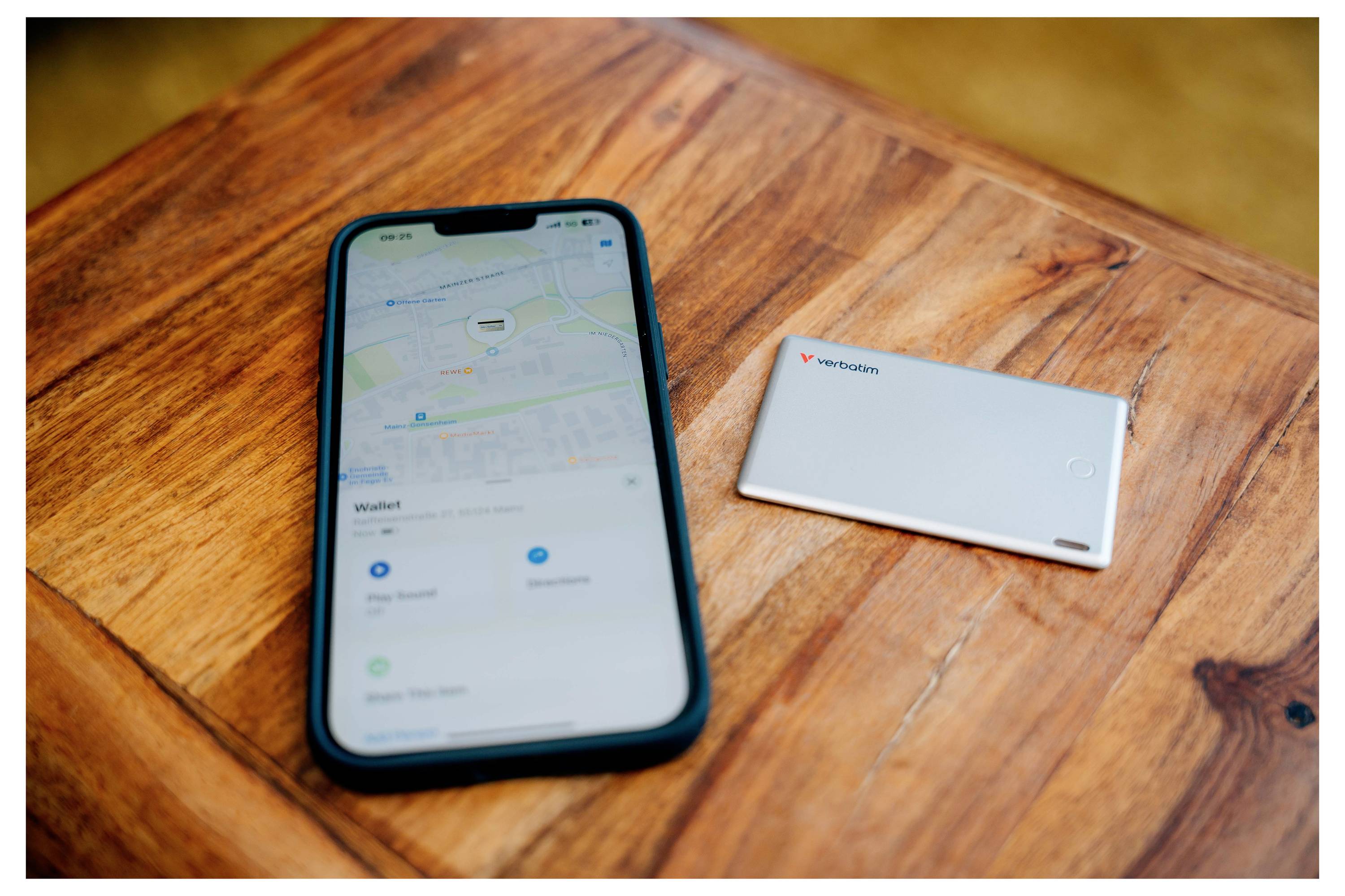 A smartphone with an open maps app is lying on a wooden table next to a white power bank.