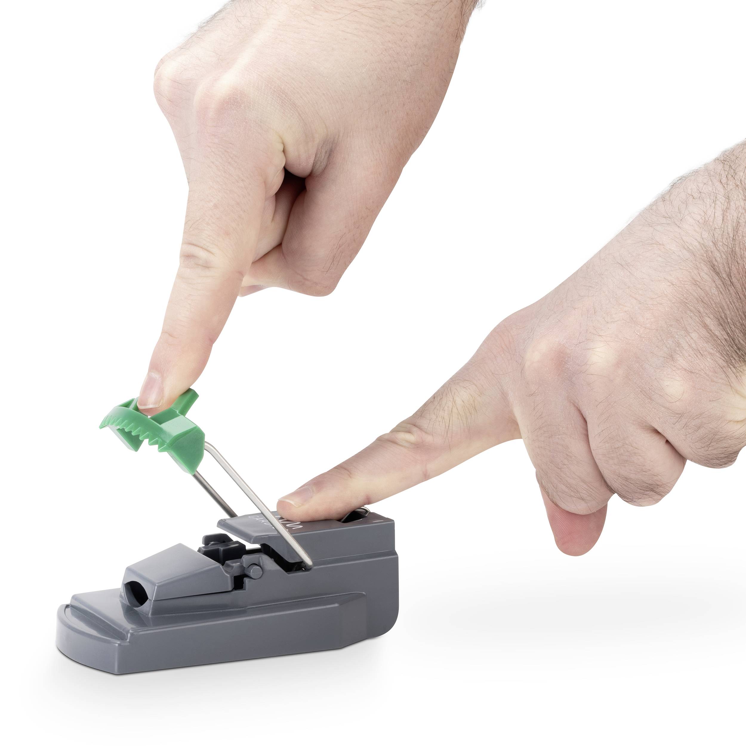 A hand is pressing a green brush into a dental floss holder mounted on a grey stand.