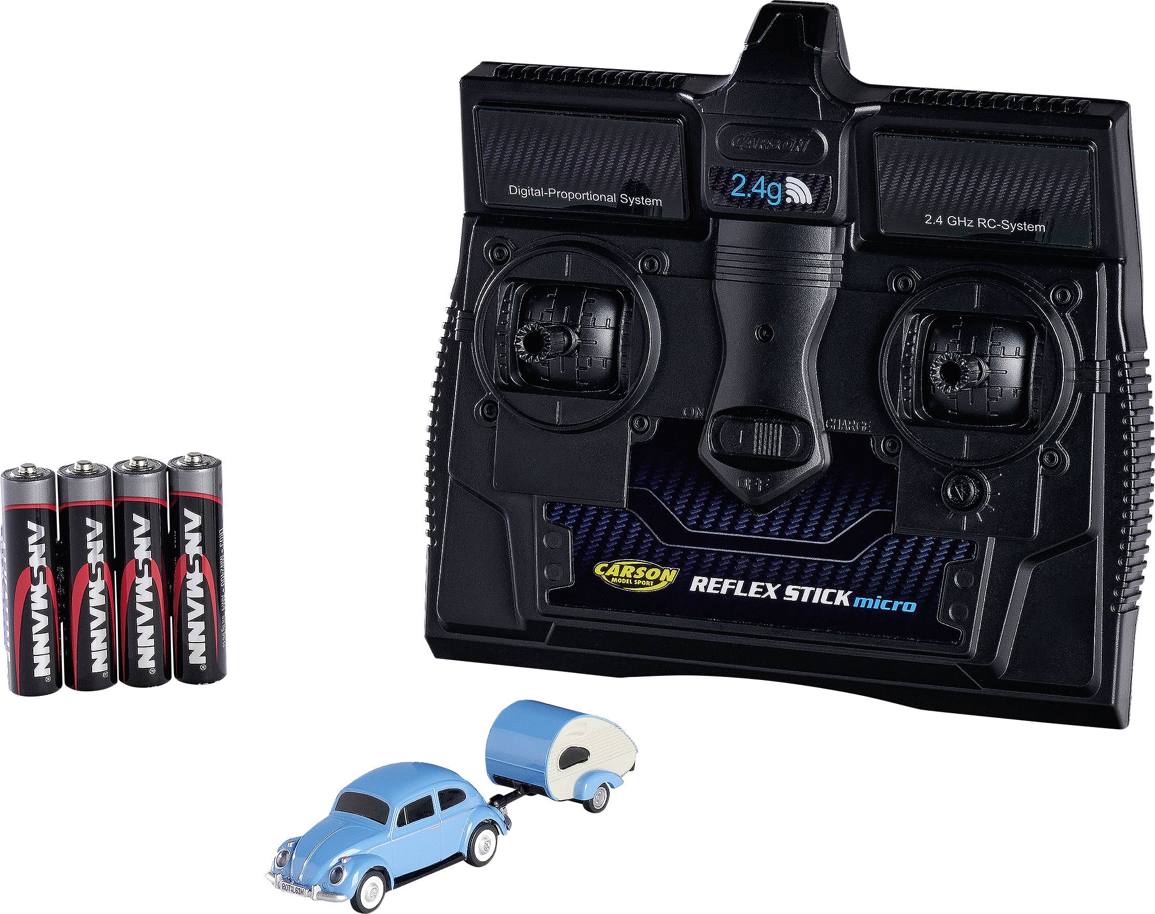 A black 2.4 GHz RC remote control with batteries and a small blue toy car with a trailer.