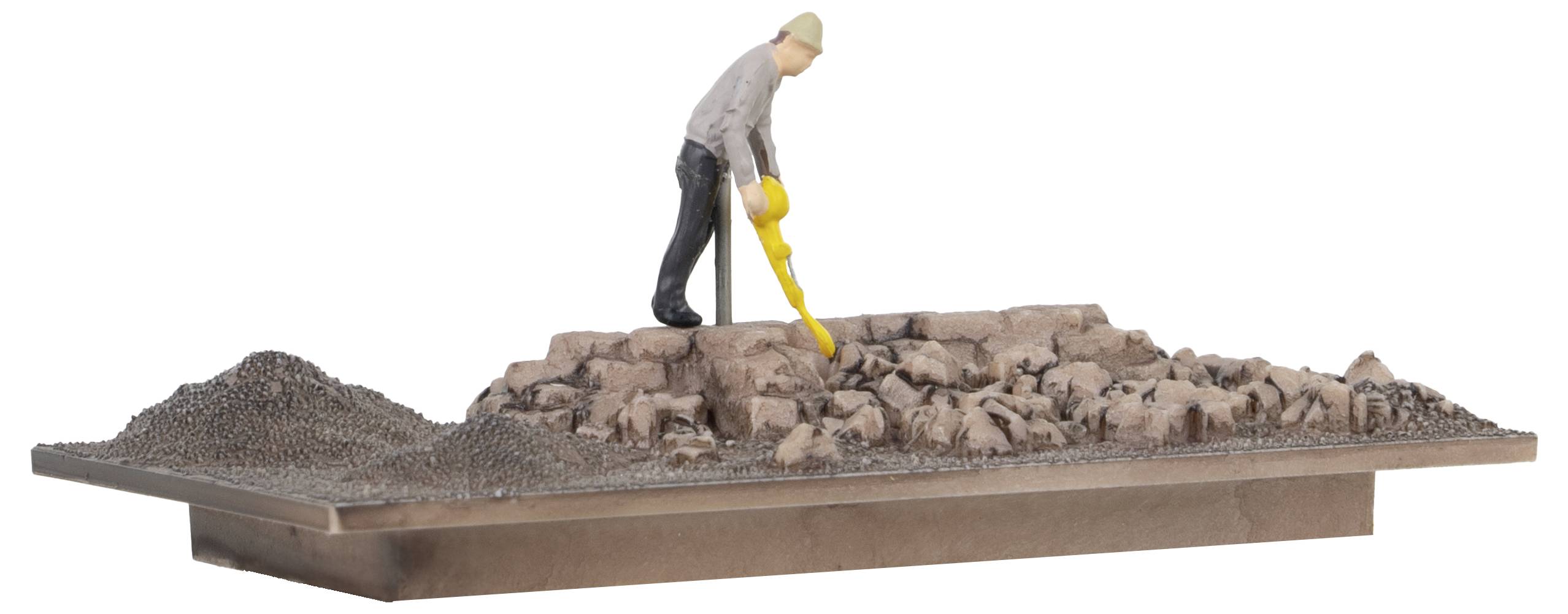 A miniature figure stands on a rock, holding a yellow device and scanning the ground.