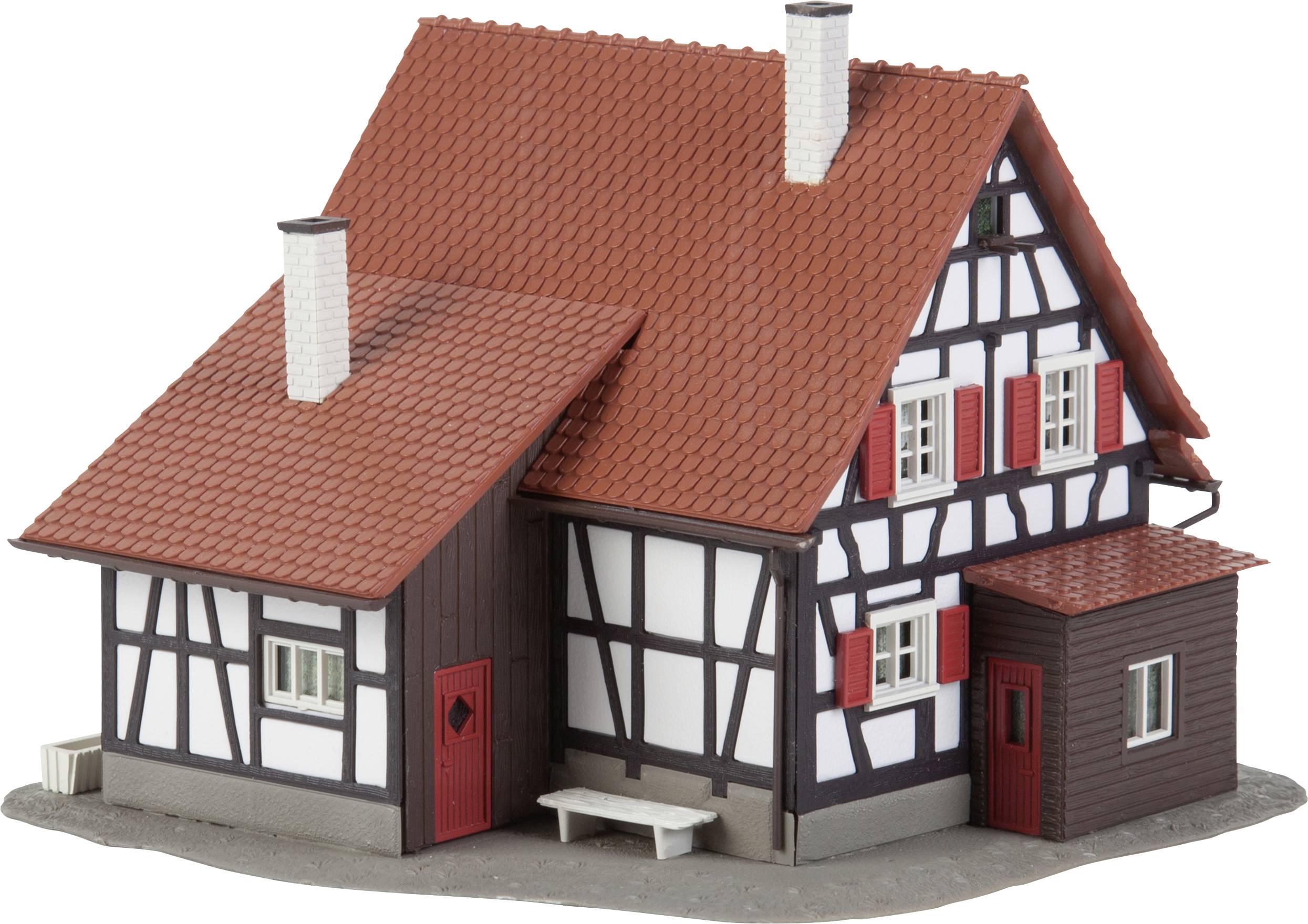 A model of a half-timbered house with a red roof and two chimneys. White walls with dark beams, red window shutters and doors.