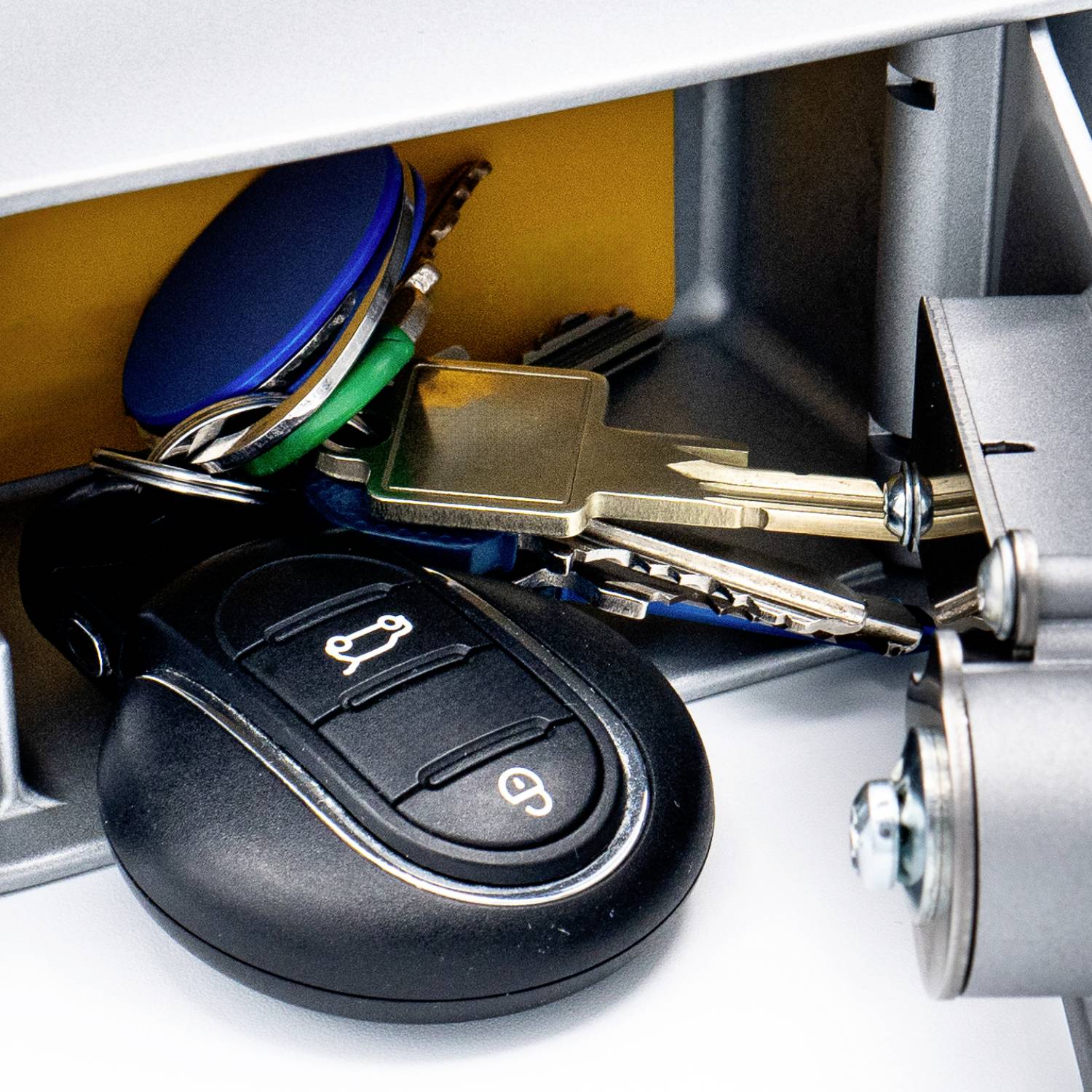 A bunch of keys with a black car key fob, lying in a metallic locker.