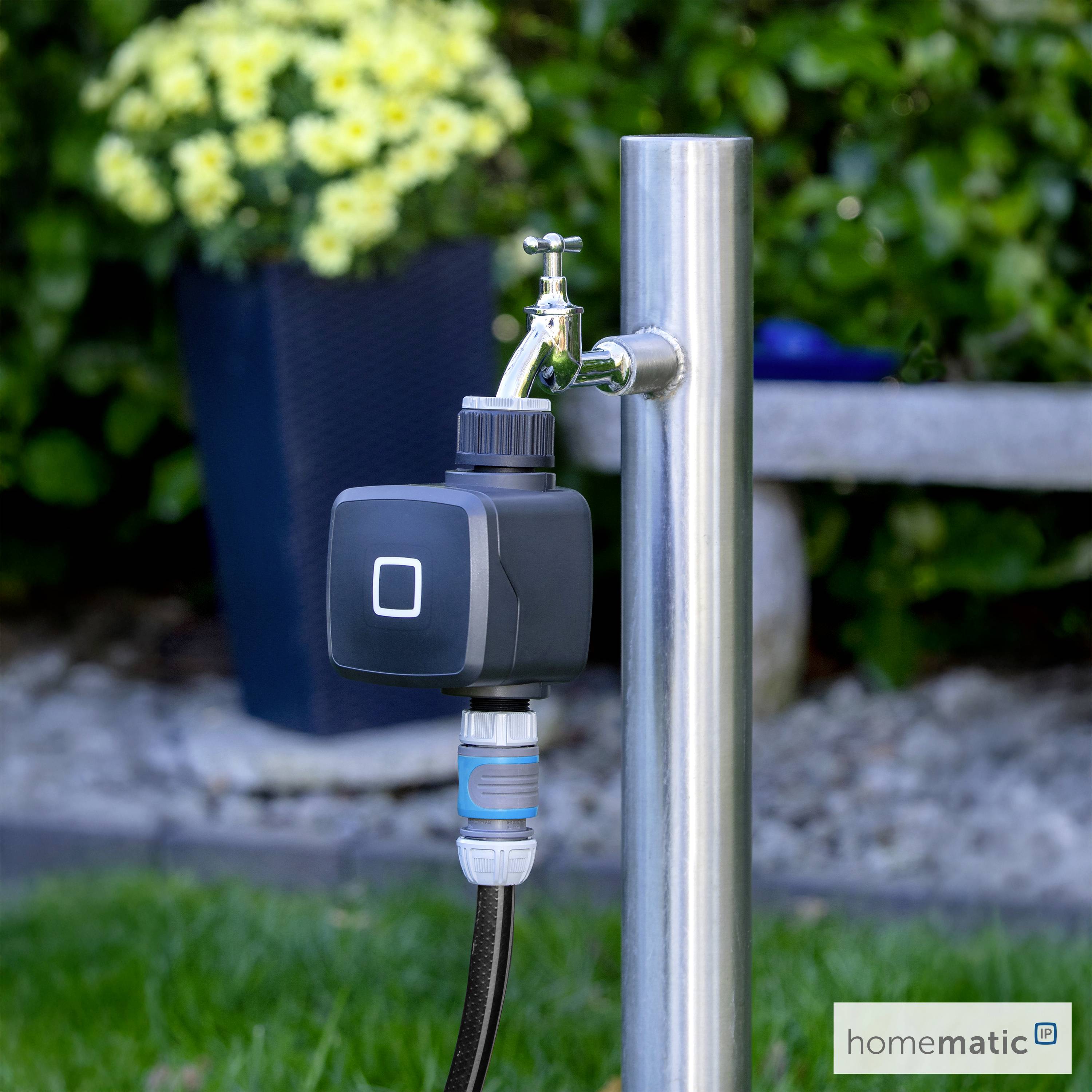 A smart water valve attached to a steel garden faucet, surrounded by green plants and flowers, illustrating modern garden technology.