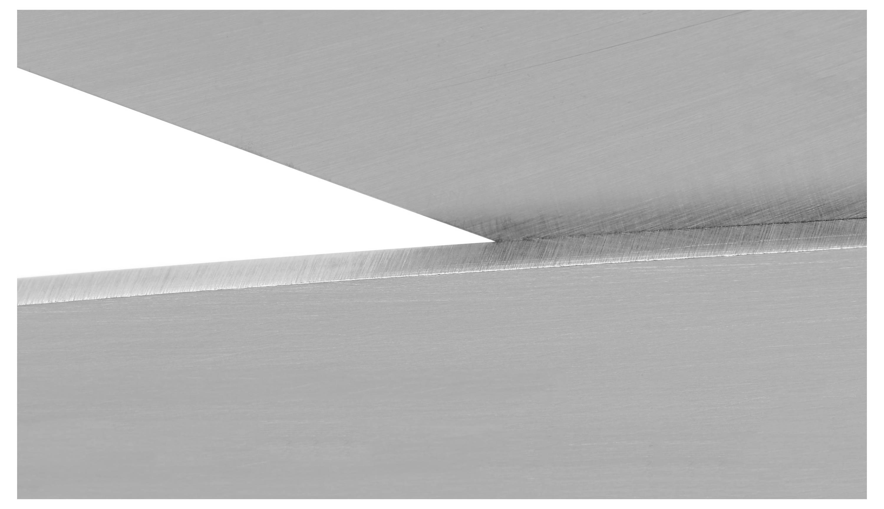 Close-up of intersecting metal sheets with a triangular gap, highlighting their smooth, reflective surfaces and sharp edges.