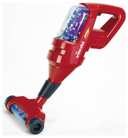A toy vacuum in red with a clear canister showing multicolored beads inside. The handle is angled, and the vacuum head has black wheels.