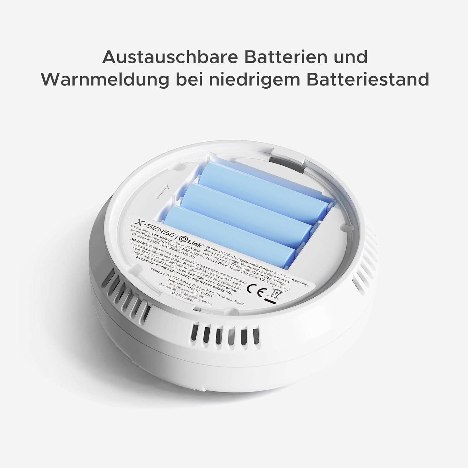 Smoke detector with battery compartment removed, showing replaceable batteries. Text: 'Replaceable batteries and low battery warning'.