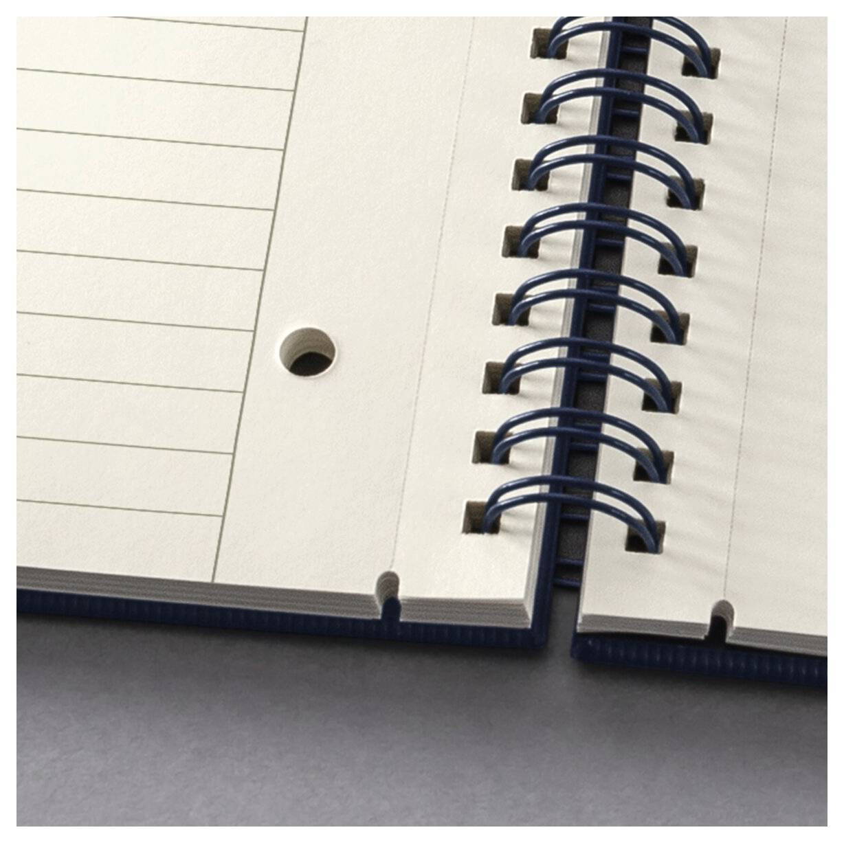 A close-up of an open spiral notebook showing lined pages with a hole for a binder. Spiral rings run through the right side.