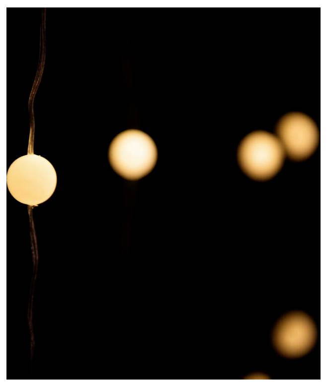 Softly glowing round string lights against a dark background, creating a warm, ambient atmosphere.