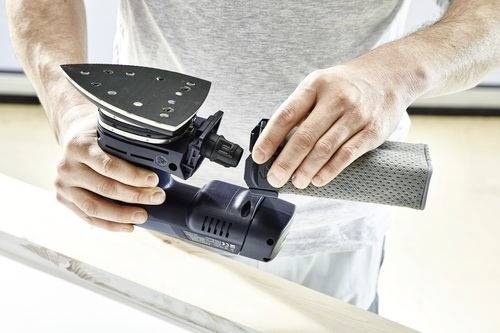 A person assembles a power tool, attaching a sanding pad to an electric sander.