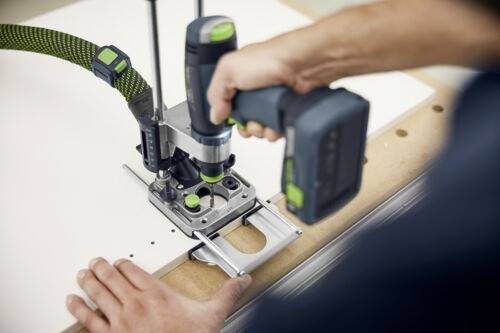 A person uses a high-precision woodworking drill press machine on a wooden board, focusing on alignment and drilling accuracy.