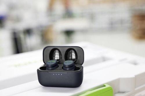 Wireless earbuds in an open charging case on a table, with a blurred background.