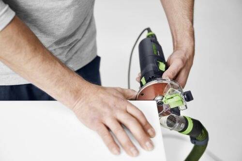 A person operates a power tool on a piece of wood, holding the tool firmly while focusing on the task.