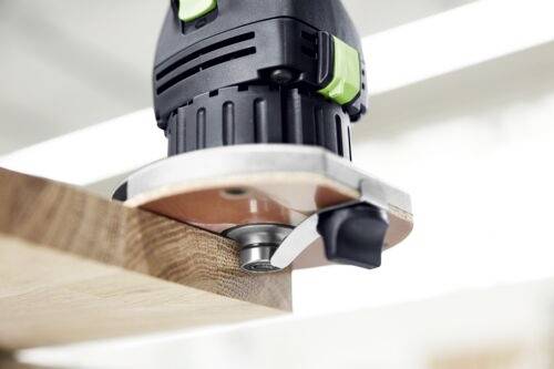 A handheld router smoothing the edge of a wooden board, highlighting woodworking craftsmanship and precise edge finishing.