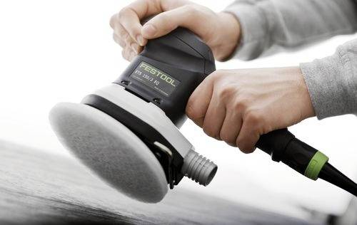 Close-up of hands using an electric sander on a wooden surface. The tool brand 'Festool' is visible on the device.
