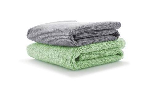 Two neatly folded towels stacked on top of each other; a gray towel on top of a green one, set against a plain white background.