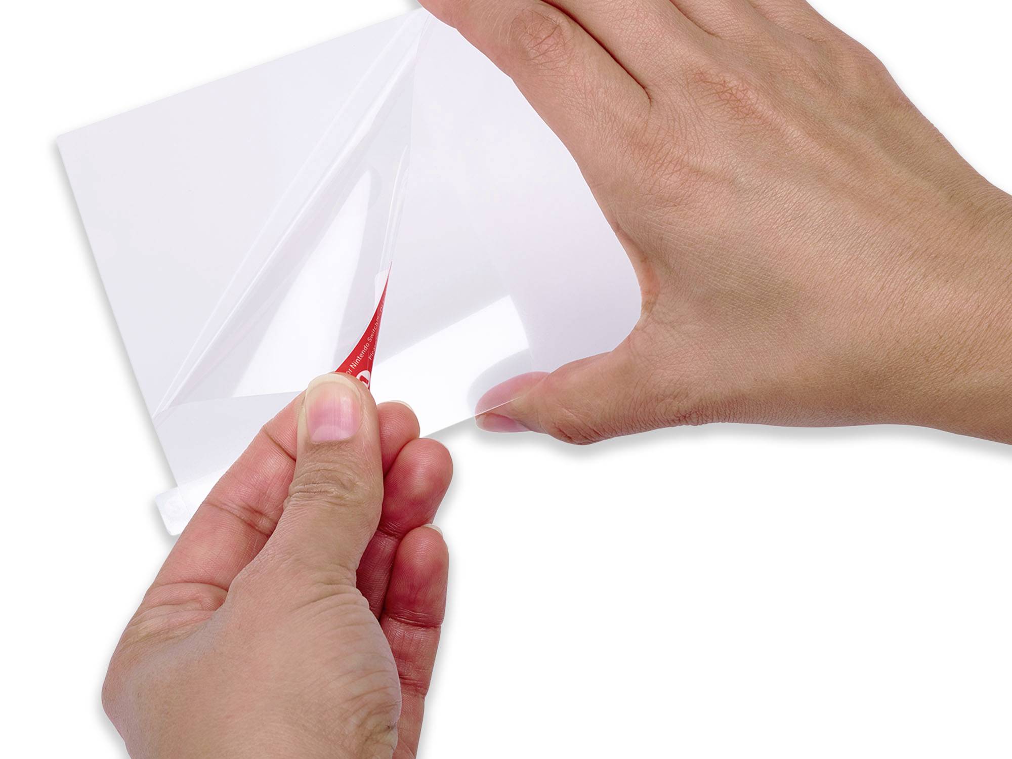 Two hands peel back a protective cover from a white plastic sheet, revealing a red layer underneath.