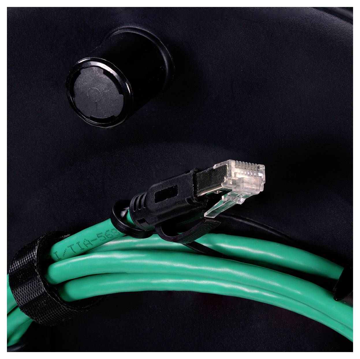 A network cable with a clear connector is coiled and secured with a black strap, positioned against a black background.
