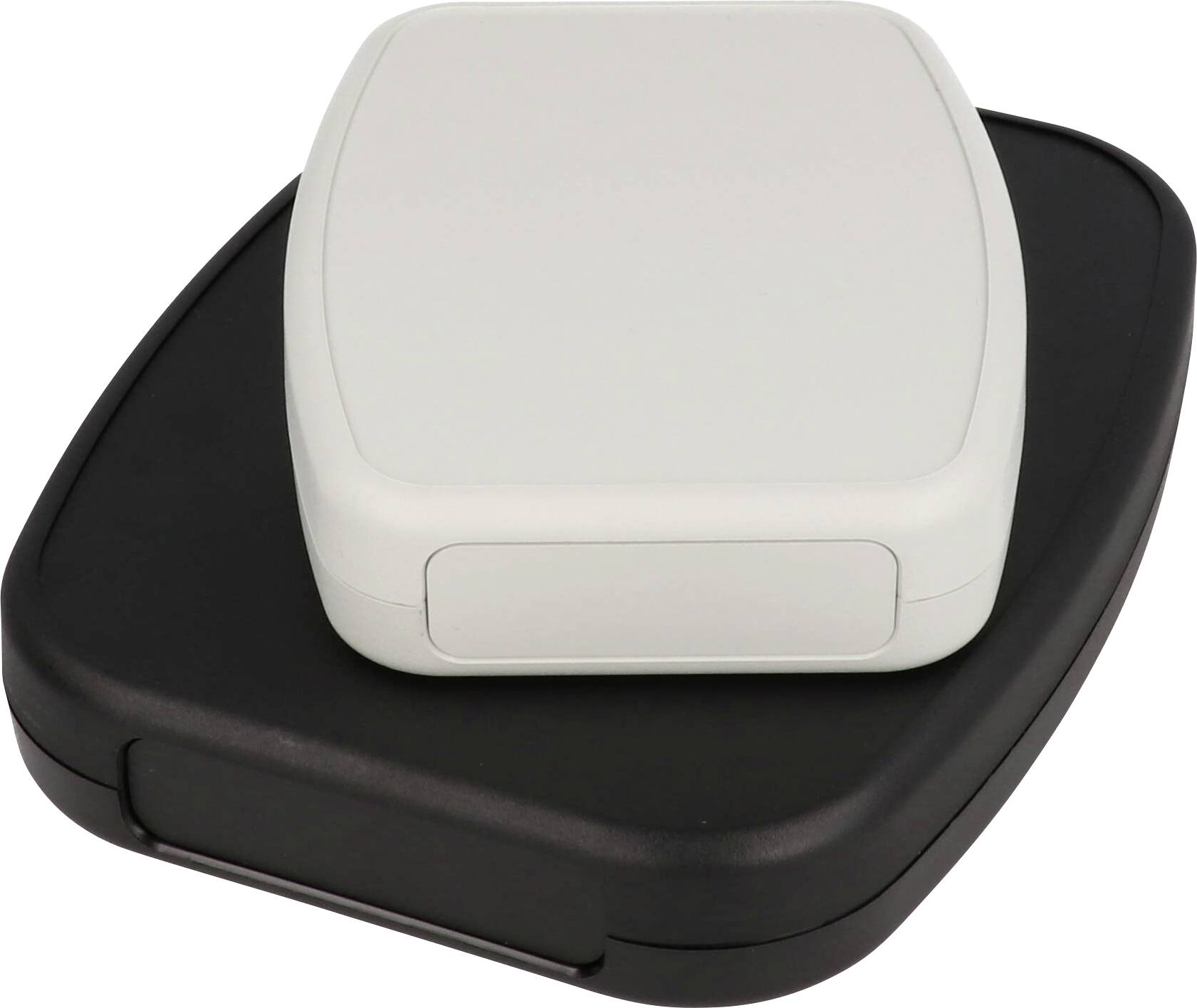A small, white, rectangular device sits on top of a larger, black, rectangular device, possibly representing a modular tech gadget.