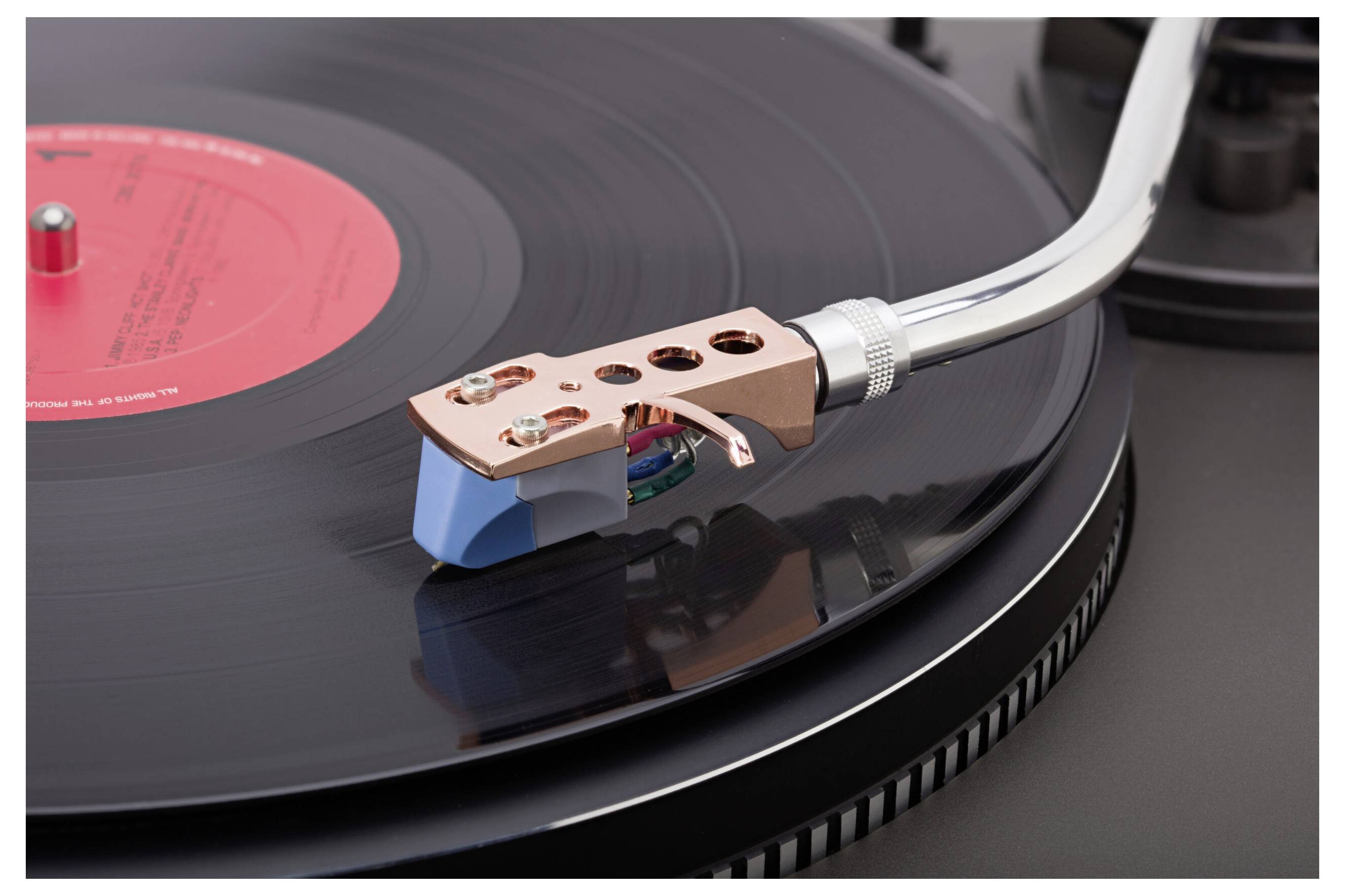 A close-up of a turntable needle on a black vinyl record, showcasing the intricate details of the tonearm and cartridge.