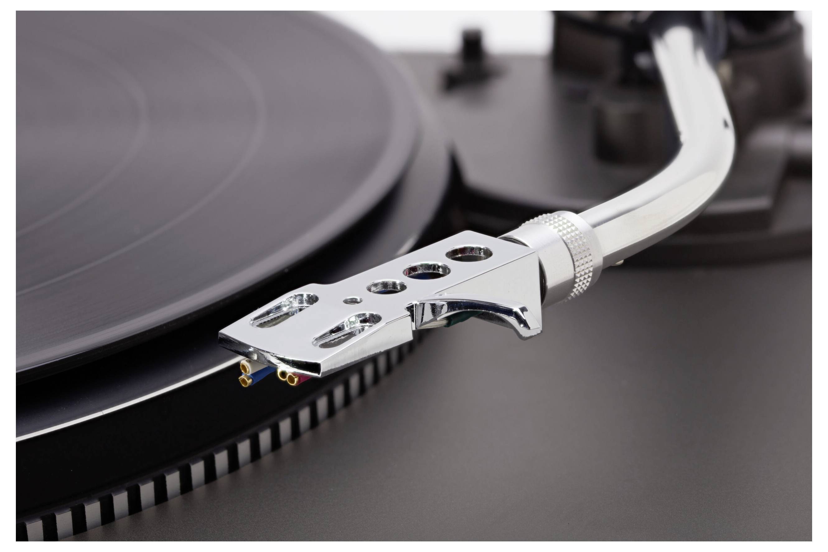 A close-up of a turntable's tonearm and needle on a black vinyl record, highlighting the mechanical precision of the audio equipment.