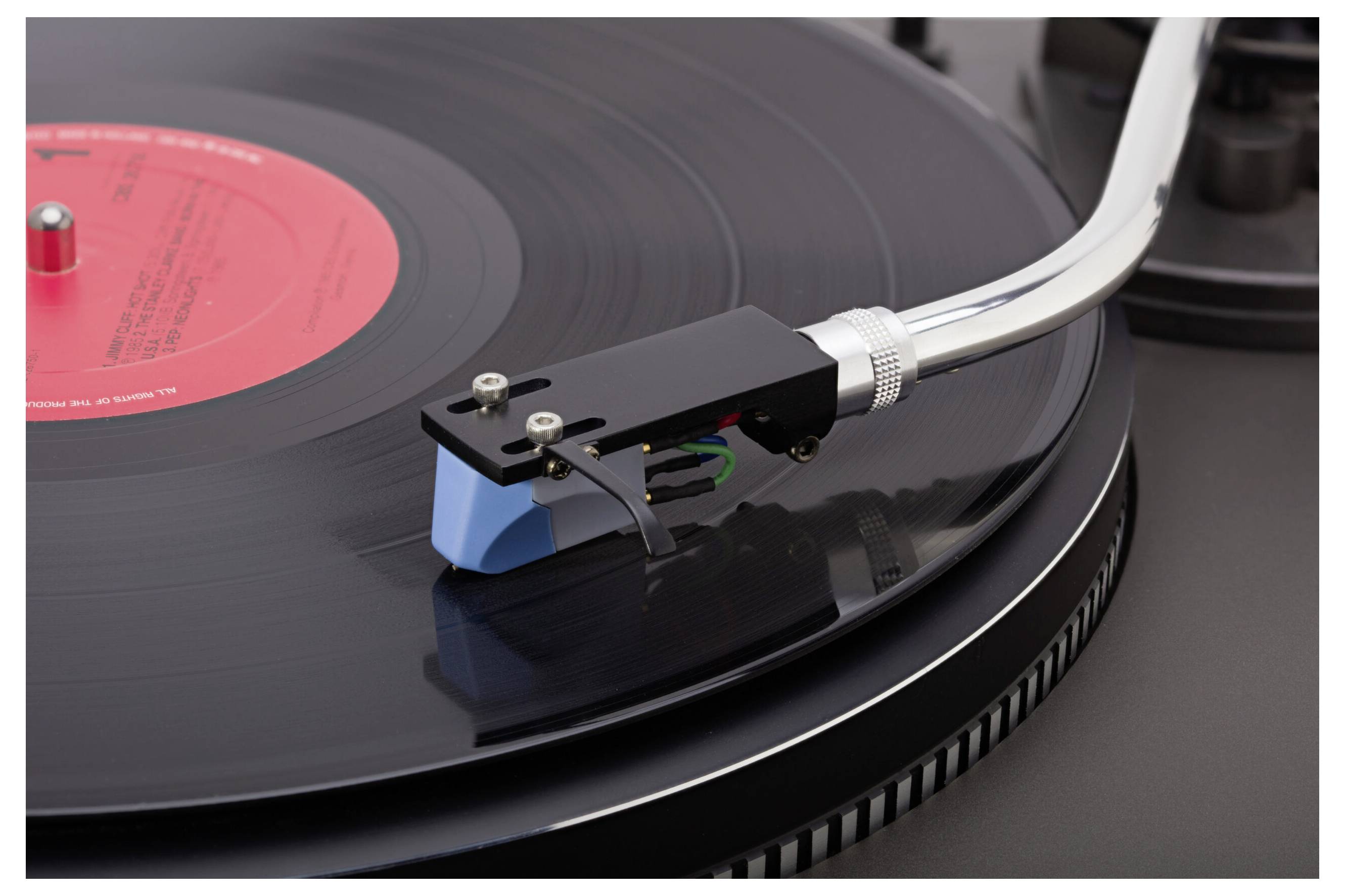 A close-up of a turntable needle on a spinning vinyl record, highlighting the grooves and label.