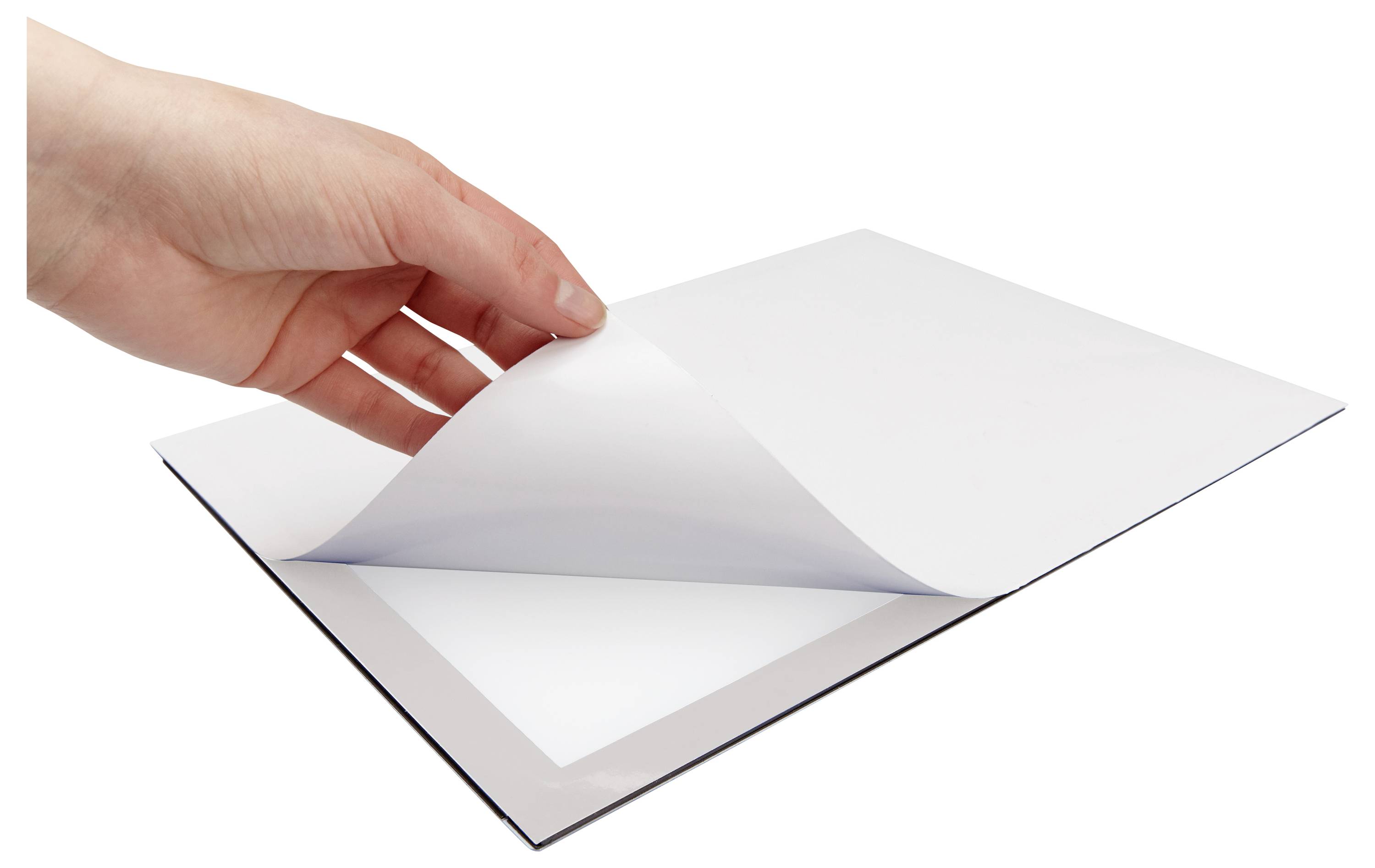 A hand lifts a sheet of white paper off a flat surface, revealing a tablet underneath.