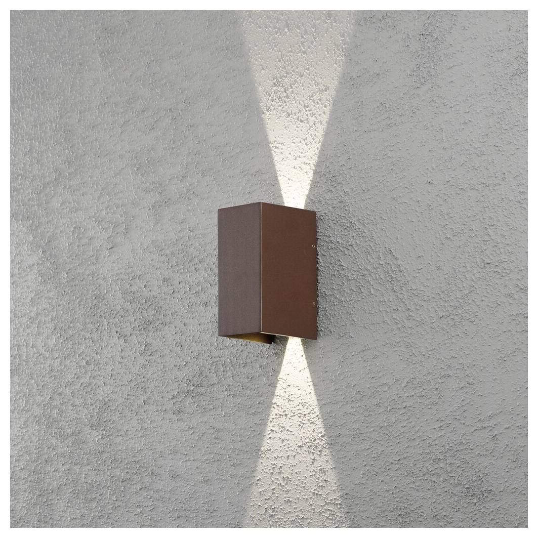 A brown wall-mounted light fixture emits a soft, upward and downward glow against a textured gray wall, creating a symmetrical pattern.