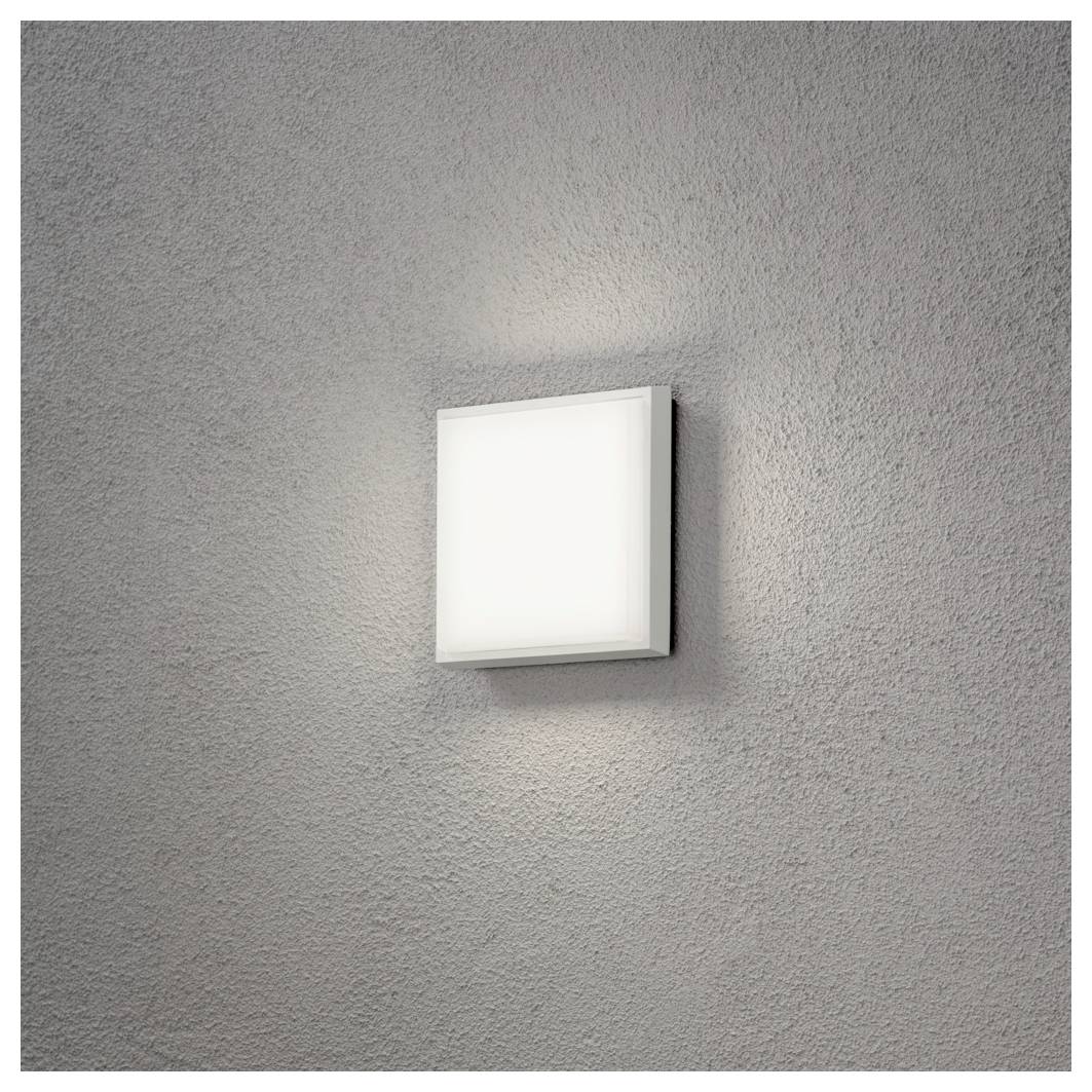 A square, wall-mounted light fixture on a textured gray wall, emitting a soft white glow.