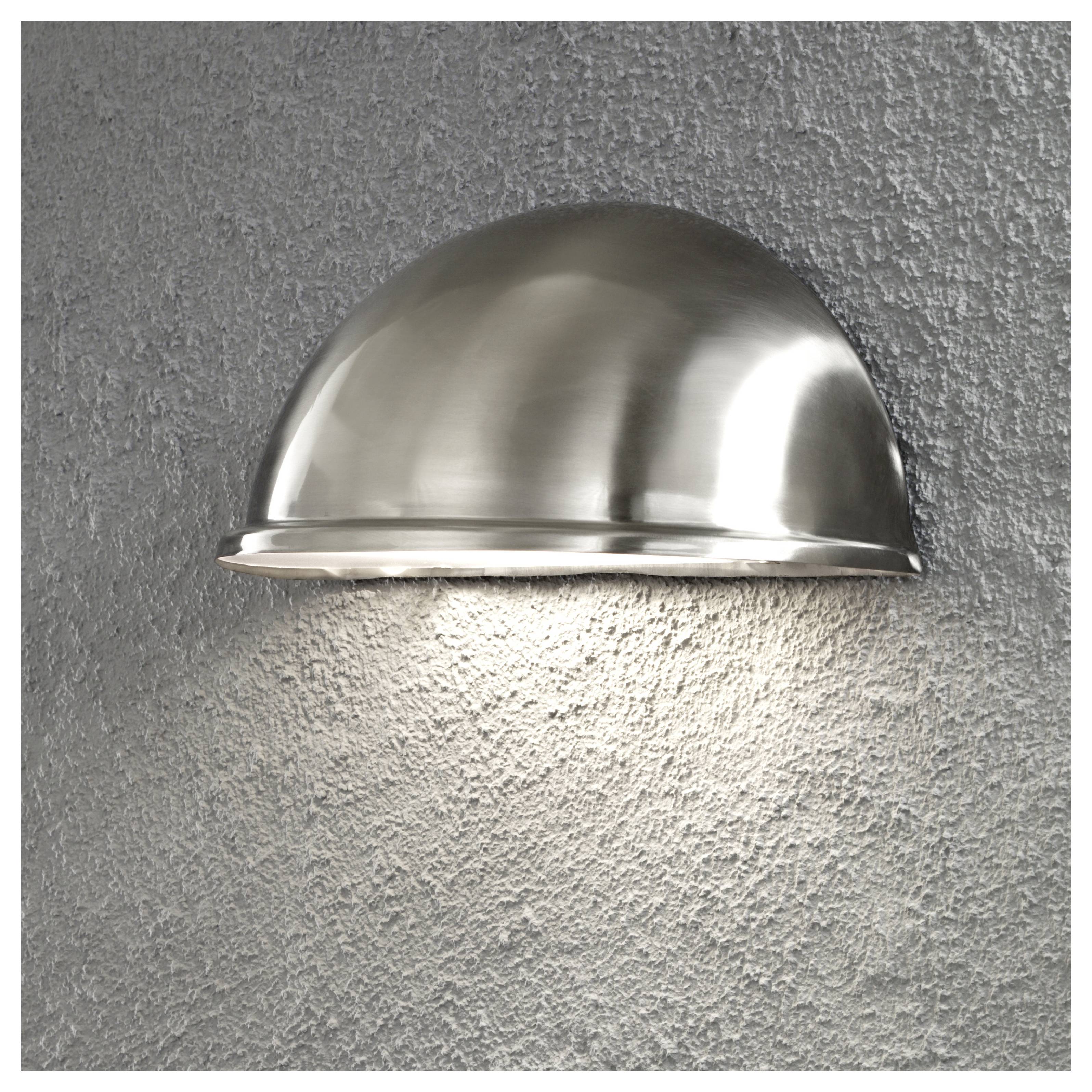 A half-sphere silver wall light fixture mounted on a textured gray wall, casting a soft downward glow.
