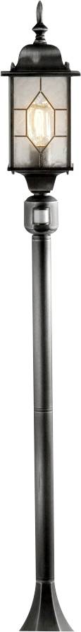 A tall, black metal outdoor lamp post with rectangular glass panes enclosing a lit bulb, featuring a classic lantern design.