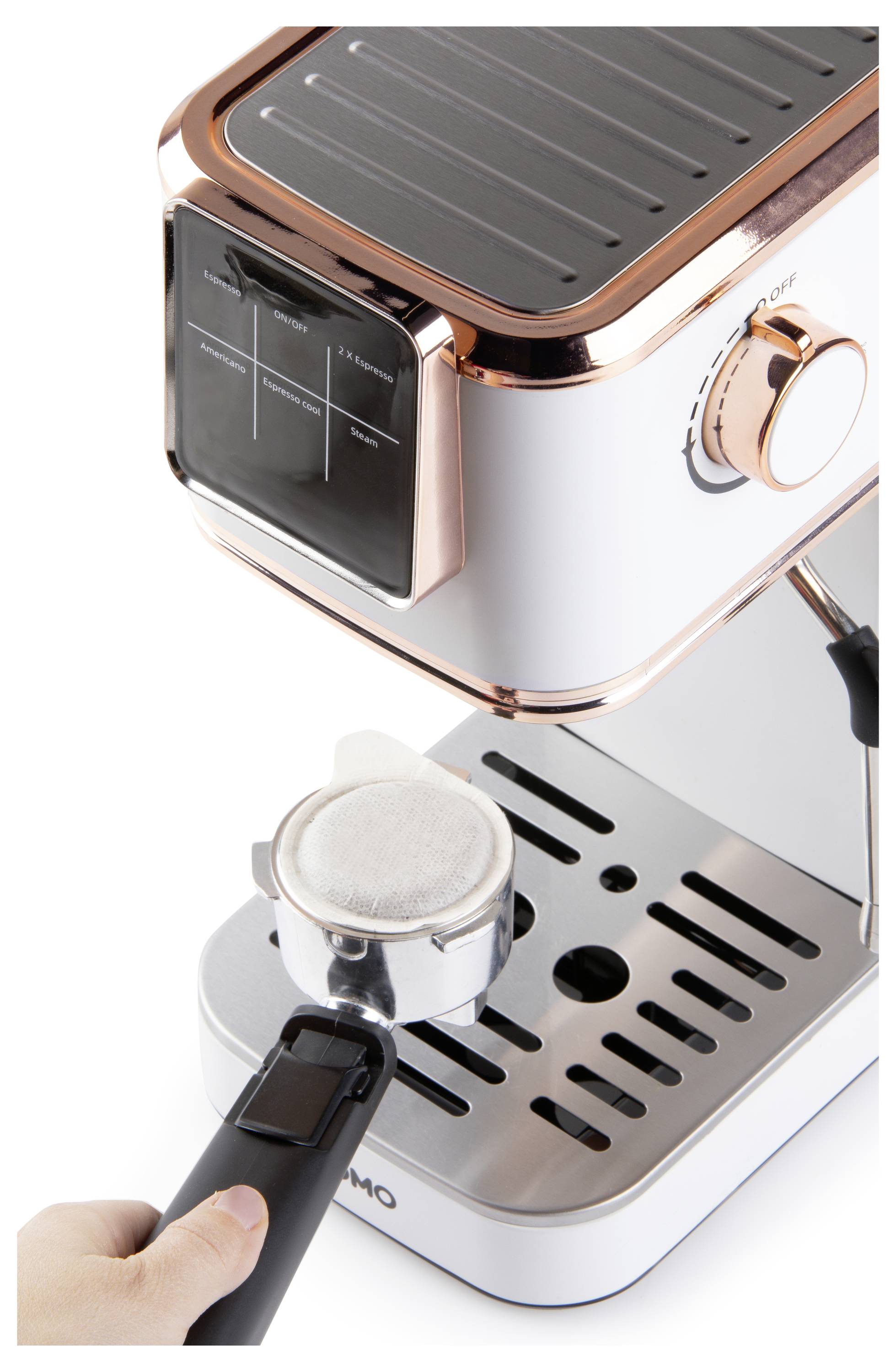 A person holds a portafilter with a white filter, ready to insert it into a modern espresso machine with copper and silver accents.