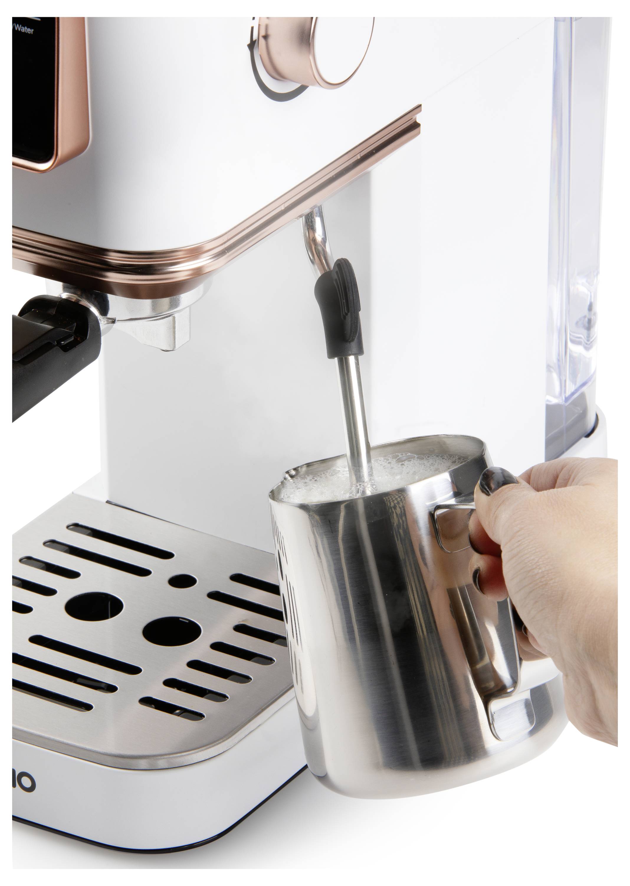 A person steaming milk with a frother attached to a white and copper espresso machine, using a metal pitcher.