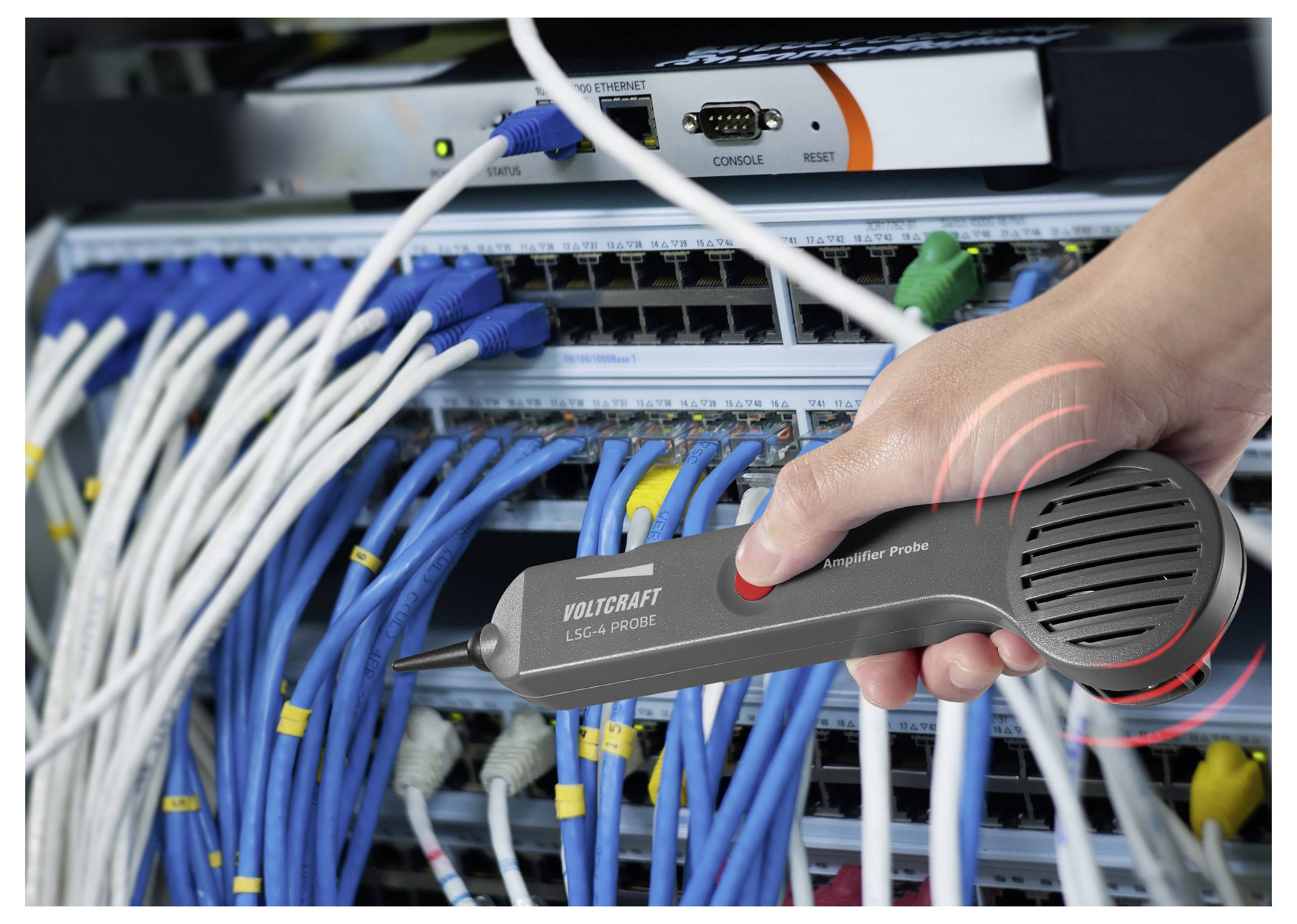 A hand holds a voltage probe near network cables connected to a server rack, indicating a signal check is being performed.